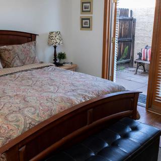 A cozy bedroom with a wooden bed, colorful bedding, and access to a small patio.