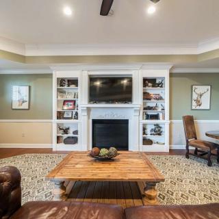 A cozy living room featuring a central fireplace with a mounted television, surrounded by built-in shelves and comfortable seating.