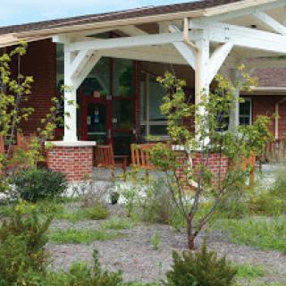 A charming house with a spacious porch surrounded by a well-maintained garden.