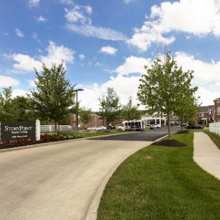 A welcoming entrance with landscaped greenery and a clear blue sky.