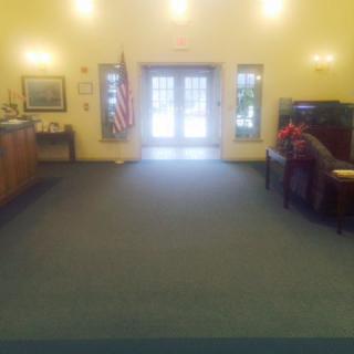 A spacious lobby area with seating, an American flag, and natural lighting.