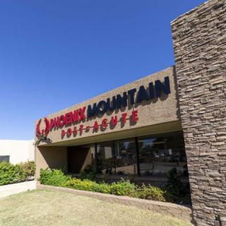 Exterior view of a restaurant with stone facade and signage on a sunny day.