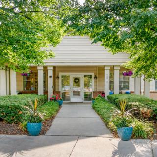 A welcoming building entrance surrounded by greenery and potted plants.