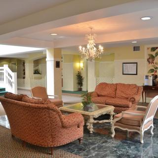 A cozy hotel lobby with comfortable seating, a chandelier, and a glass coffee table.
