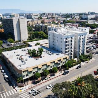 Aerial view of a cityscape featuring multiple buildings, streets, and traffic with trees lining the roads.