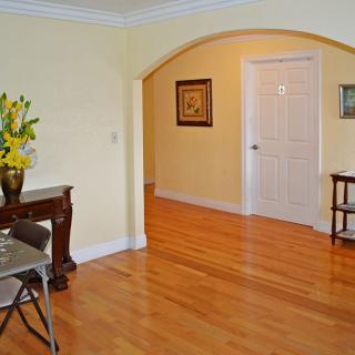 A well-lit living room with hardwood floors and elegant decor, featuring an archway leading to another area.