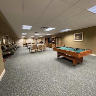 A spacious game room featuring a pool table and various seating areas.