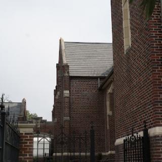 A glimpse of a historic brick building, showcasing intricately designed architecture against a gray sky.