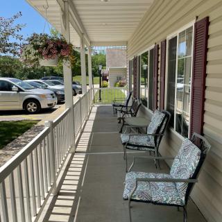 A sunny porch with comfortable chairs and hanging plants.