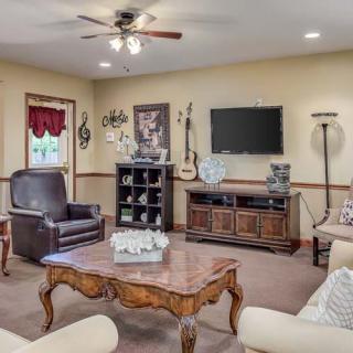 A cozy living room with a mix of traditional and modern decor, featuring a television, armchairs, sofas, a coffee table, and decorative items including a guitar.