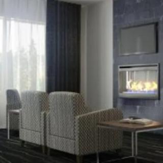 A modern living room with cozy chairs facing a fireplace and television.