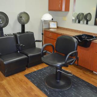 A modern hair salon setup featuring a styling chair, waiting area, and hair dryers.