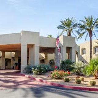A hotel entrance surrounded by desert landscaping and palm trees.