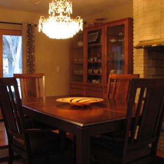 A cozy dining room with a wooden table and chairs illuminated by a chandelier.