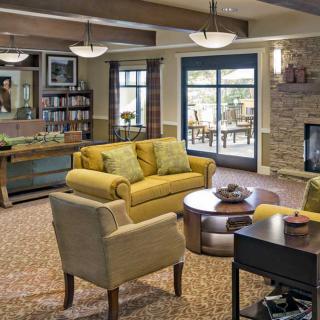 A cozy living room with a yellow sofa, armchair, and a fireplace.