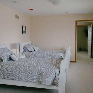 A minimalist bedroom with twin beds and neutral-colored decor.