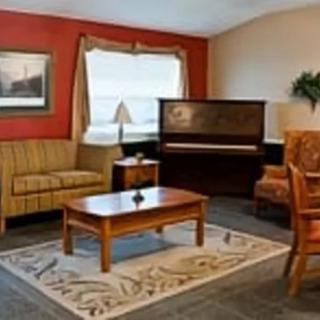 A cozy living room featuring a sofa, piano, and wooden furniture.