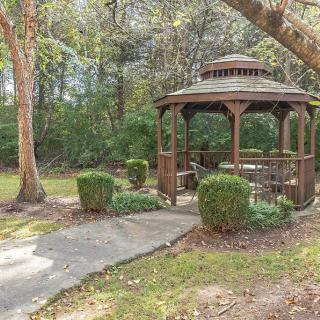 A peaceful garden setting with a wooden gazebo surrounded by trees and greenery.