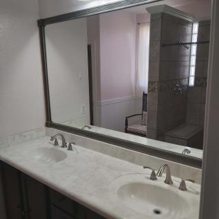 A modern bathroom with a large mirror and double sinks.