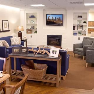 A cozy living room with sofas, chairs, and a television above the fireplace surrounded by shelves.