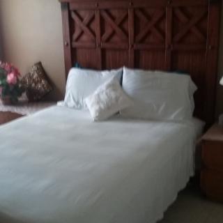 A neatly made bed with white bedding and a wooden headboard.