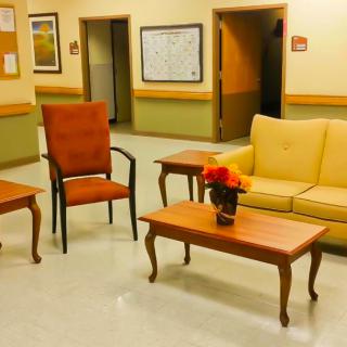 A cozy waiting area with a sofa, chairs, and tables adorned with a flower arrangement.