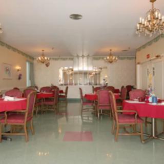 A spacious dining room with red tablecloths and elegant chandeliers.