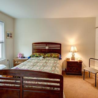 A cozy bedroom with a wooden bed, nightstand, and lamp.