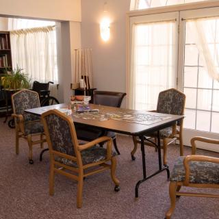 A cozy dining room with a table and chairs, featuring large windows.
