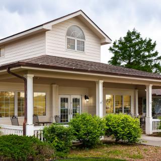 A cozy two-story suburban house with a spacious porch and well-maintained landscaping.