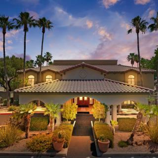 A resort entrance surrounded by palm trees at sunset.