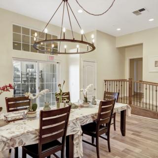 A stylish dining room featuring a modern chandelier and wooden furniture with a beautifully set table.