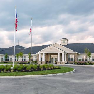 A large building with a grand entrance and flags out front under a cloudy sky.