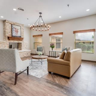 A cozy and modern living room featuring comfortable seating, a stylish chandelier, and a warm fireplace.