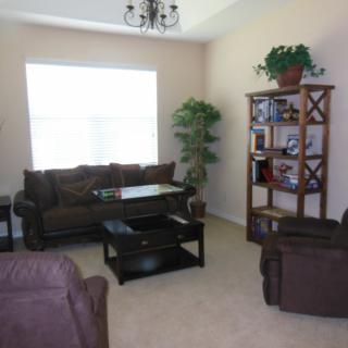 A cozy living room with brown furniture and a large window letting in natural light.