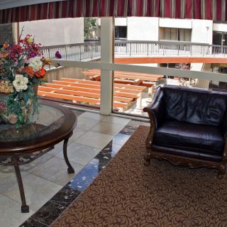 A lobby area with a leather chair and a table adorned with a flower arrangement, overlooking a window view.