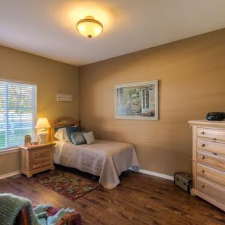 A cozy bedroom with a single bed, wooden furniture, and soft lighting.