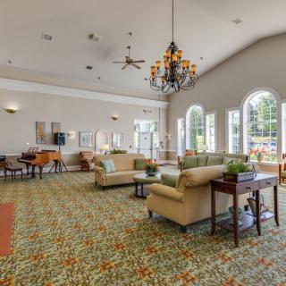 A spacious and well-decorated lounge area featuring comfortable sofas, a chandelier, large windows, and stylish decor.