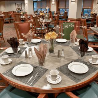An elegantly set dining table in a restaurant, complete with place settings and floral centerpiece.