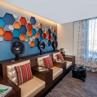 A modern salon seating area with colorful hexagonal wall art and built-in hair dryers.