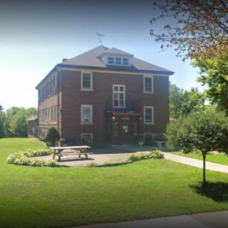 A brick building surrounded by a well-maintained lawn and trees on a sunny day.