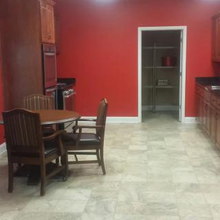 A kitchen with red walls, wooden furniture, and a tile floor.