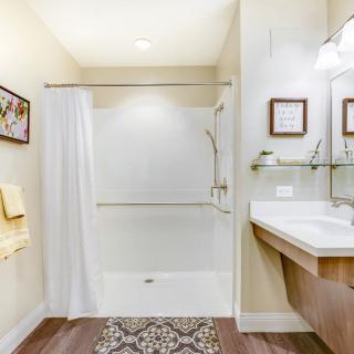 A clean and modern bathroom featuring a shower with a white curtain, a sink, and decorative elements.