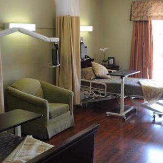 A hospital room featuring a medical bed, chair, and healthcare equipment.