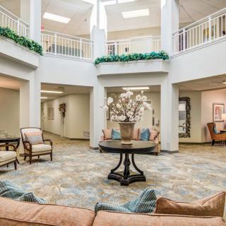 A spacious and elegantly designed lobby area featuring comfortable seating, decorative plants, and natural lighting.