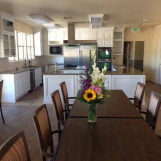 A modern kitchen and dining area with a vase of flowers on the table.