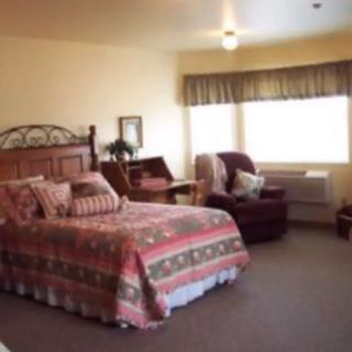 A cozy hotel room featuring a large bed, armchair, and window.