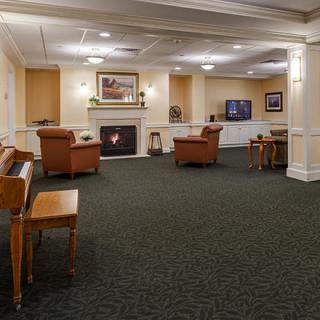 A cozy lobby area featuring comfortable seating, a piano, and a fireplace.