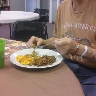 A person is eating a meal at a table with a plate of food.