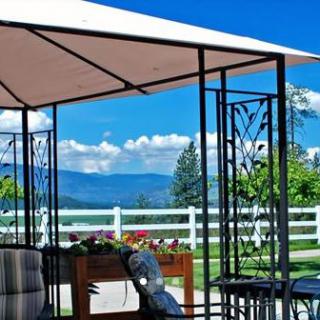 A scenic view from a patio under a gazebo, overlooking mountains and a white fence.